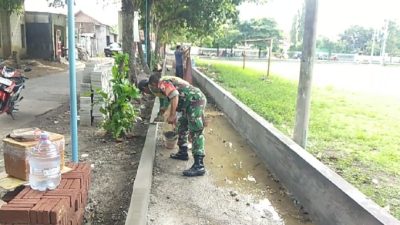 Babinsa Bantu Warga Bangun Pembatas Trotoar di Desa Pandantoyo